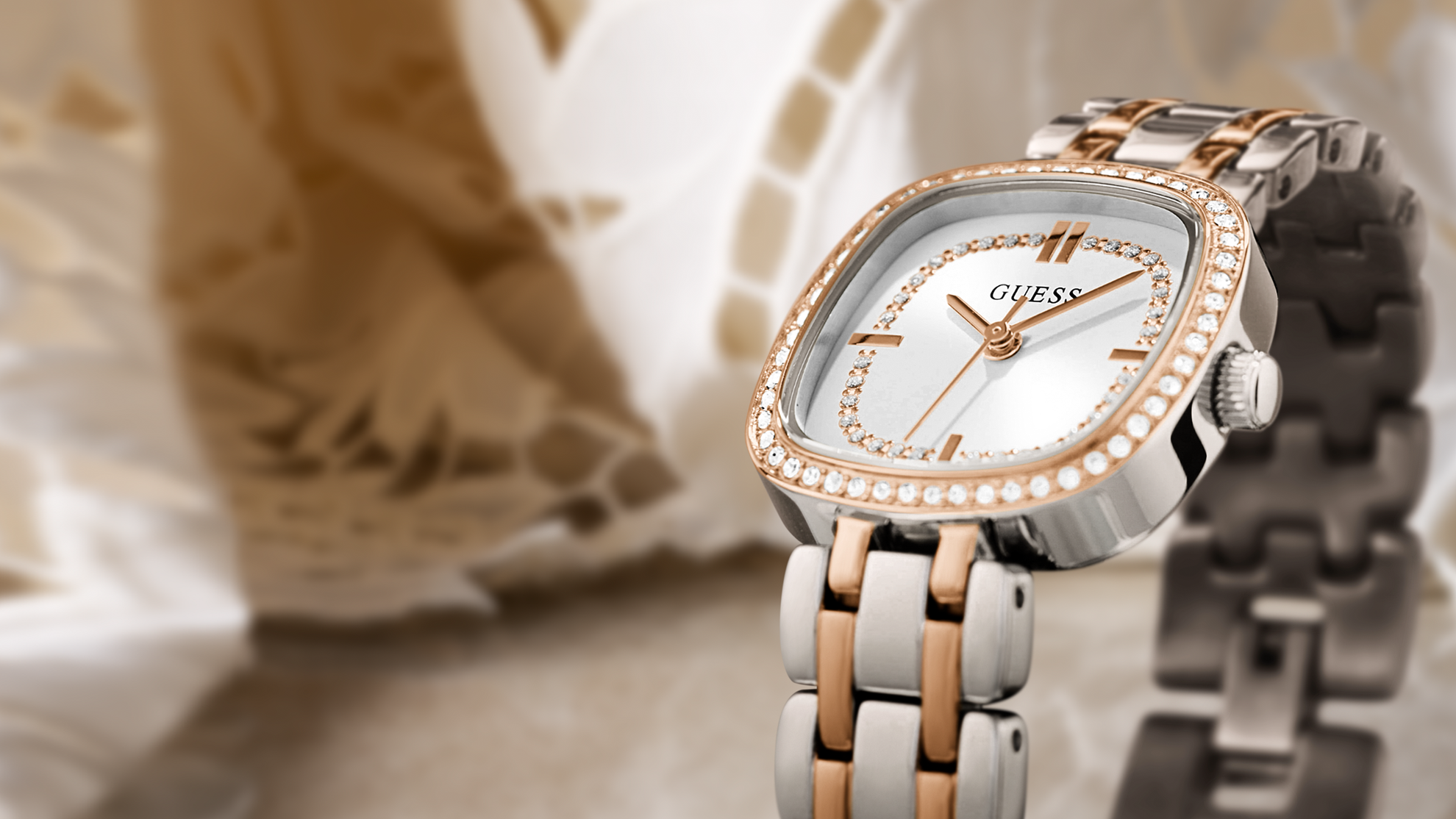 Close up of Guess watch with rose gold and silver band on a blurred background