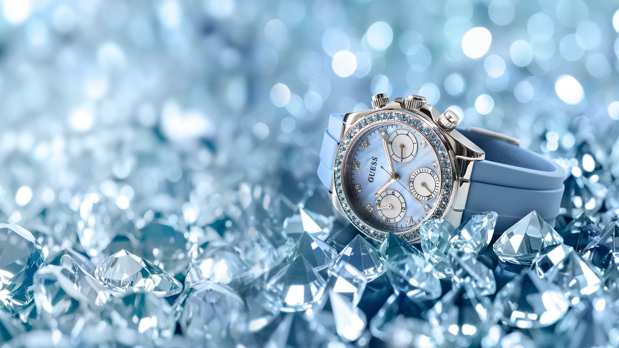 Luxury GUESS Ladies Ice Blue Silver Tone Analog Watch with Swarovski ReCreated™ crystals with blue strap on a glittery diamond-like crystal surface