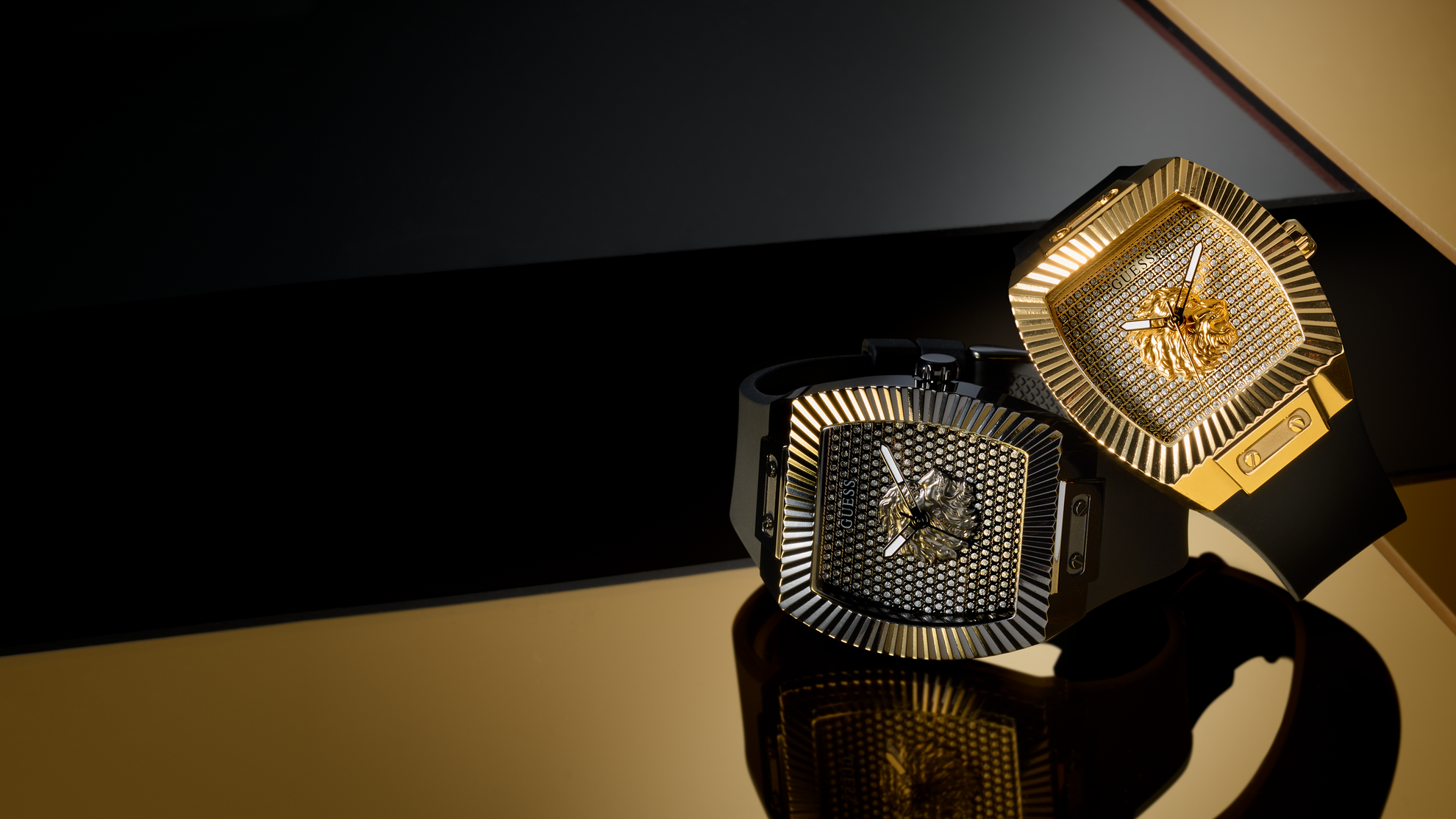 Two gold and black square watches on a reflective surface with a dark background