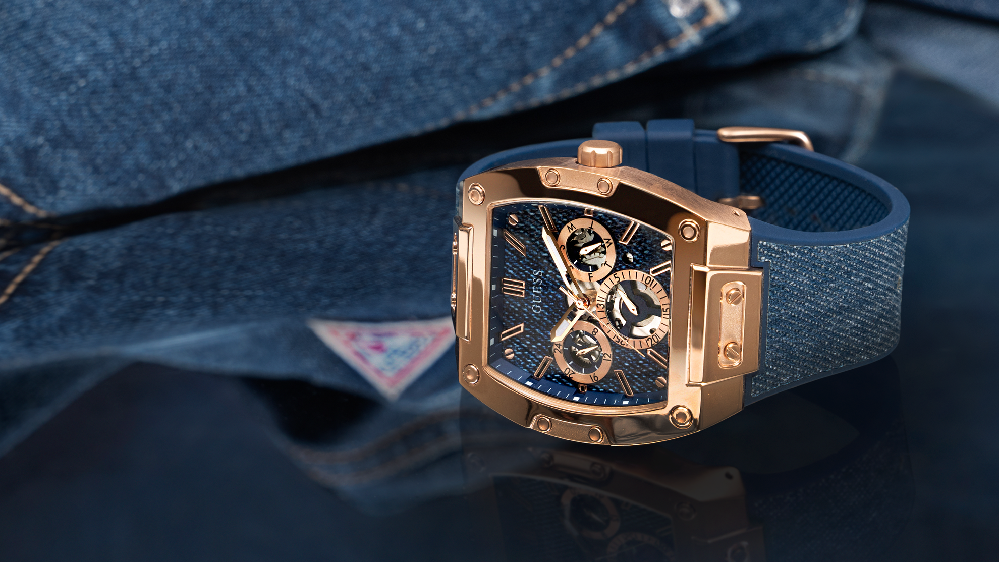 Luxury watch with blue strap on a reflective surface with denim gw0786g2
