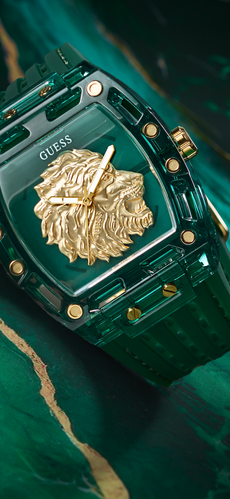Green watch with gold lion emblem and 'Guess' branding on a dark background