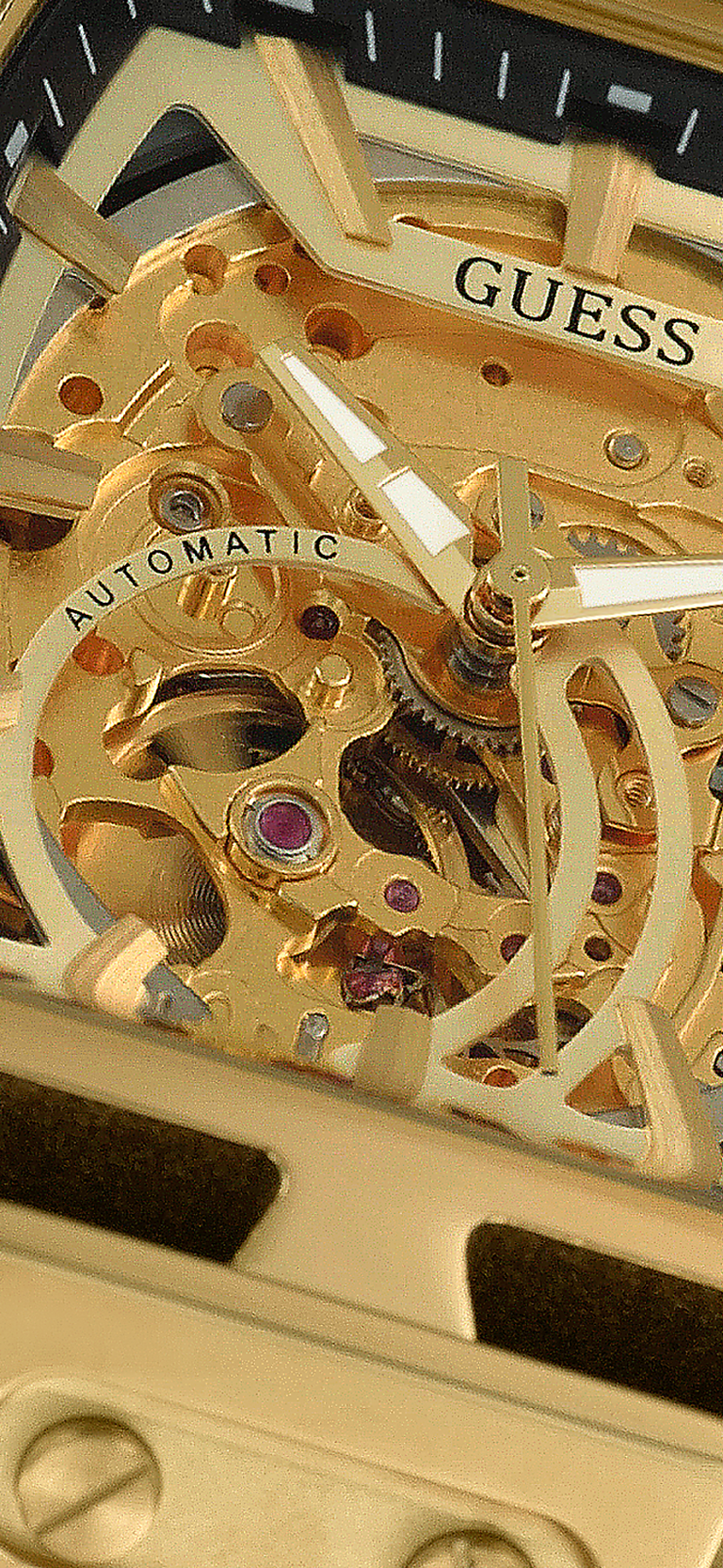 Close-up of a gold watch automatic mechanism with 'Guess' branding.