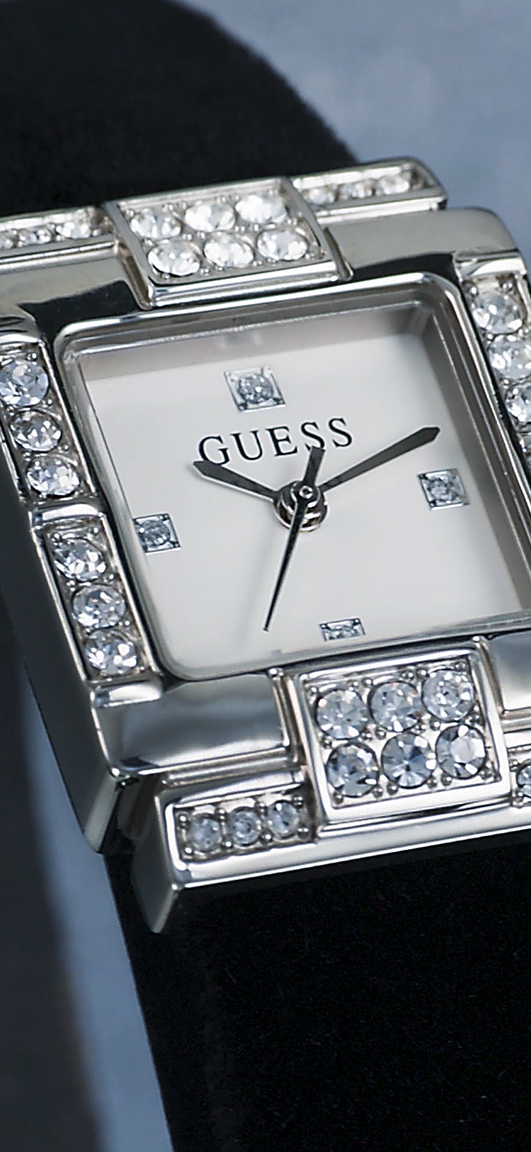 Silver Guess watch with gemstone accents on a dark background
