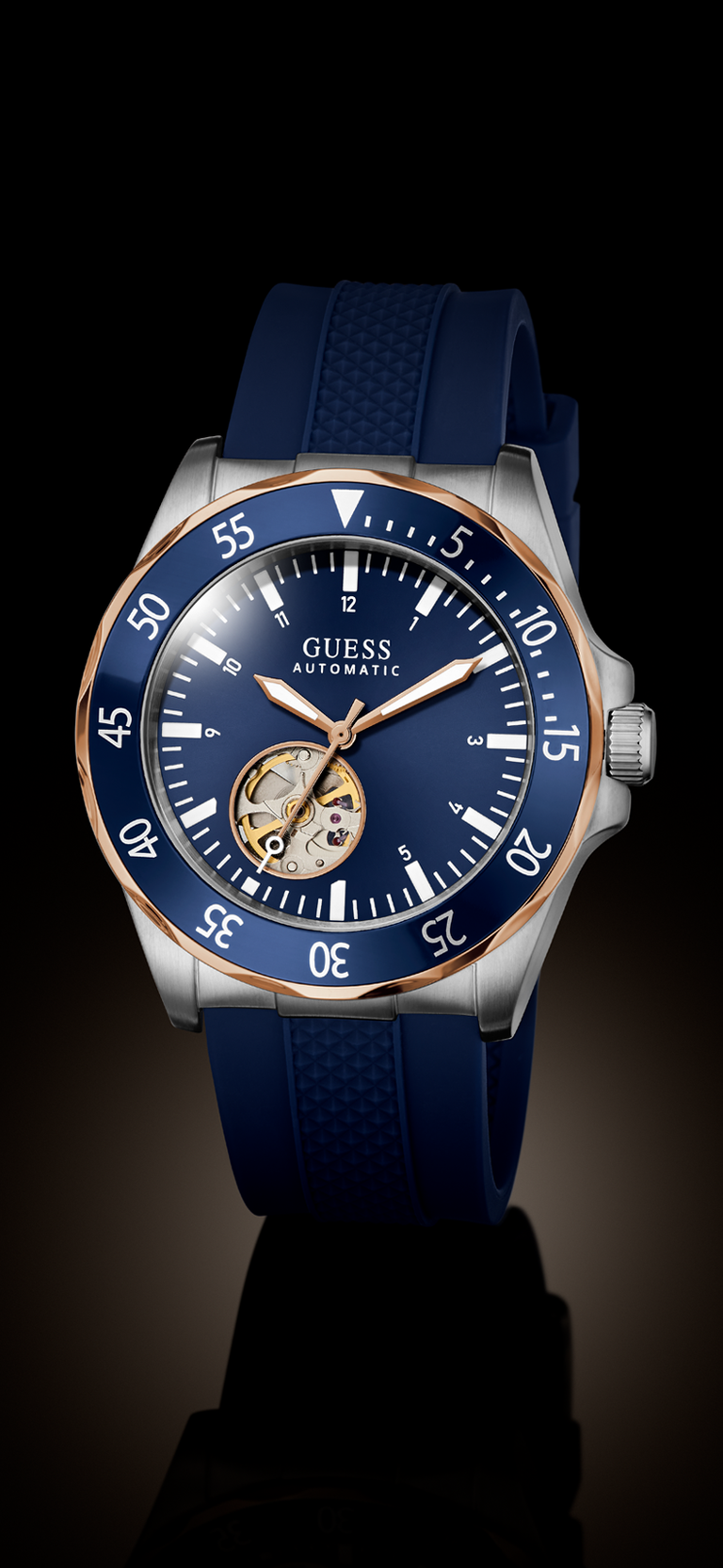 GUESS Automatic watch with a blue dial, blue textured strap, and a silver-toned case accented with a rose gold bezel and hands.