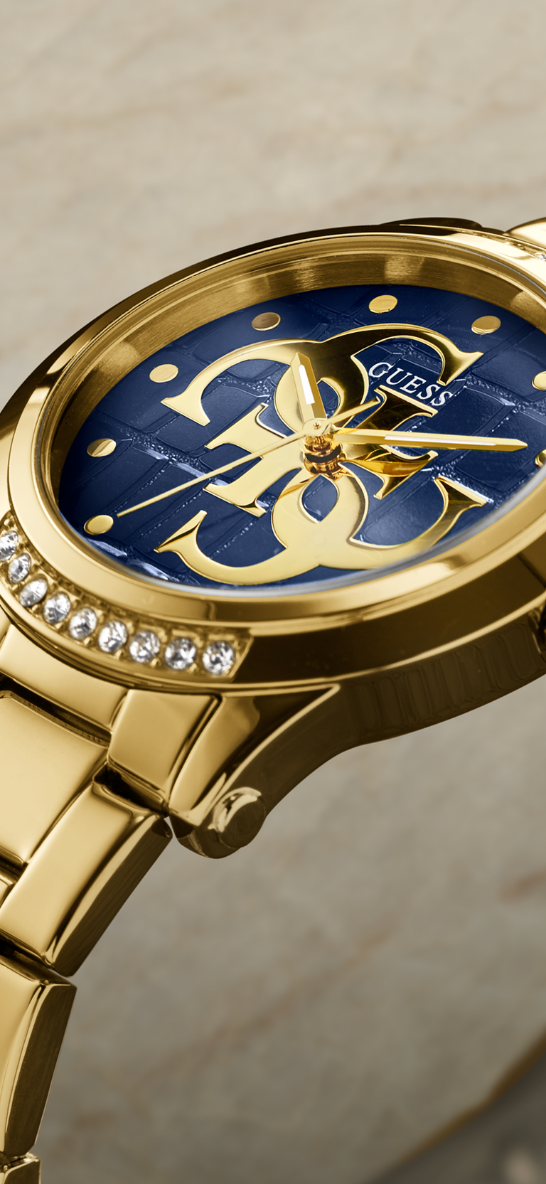 Gold watch with a blue face featuring a logo on a beige background
