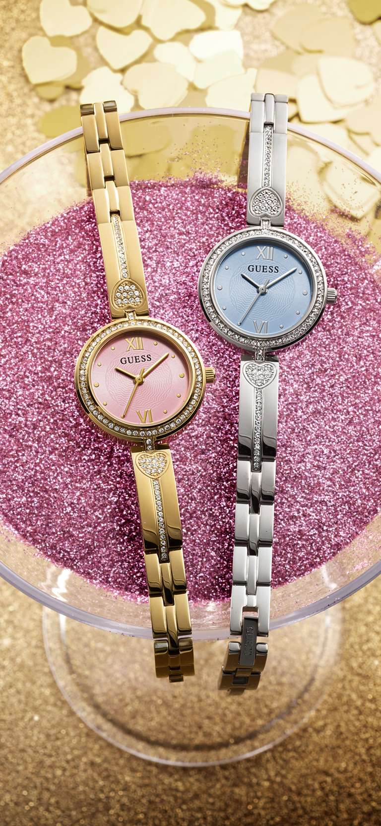 Two GUESS Watches in silver and gold with pink and blue dials on a martini glass