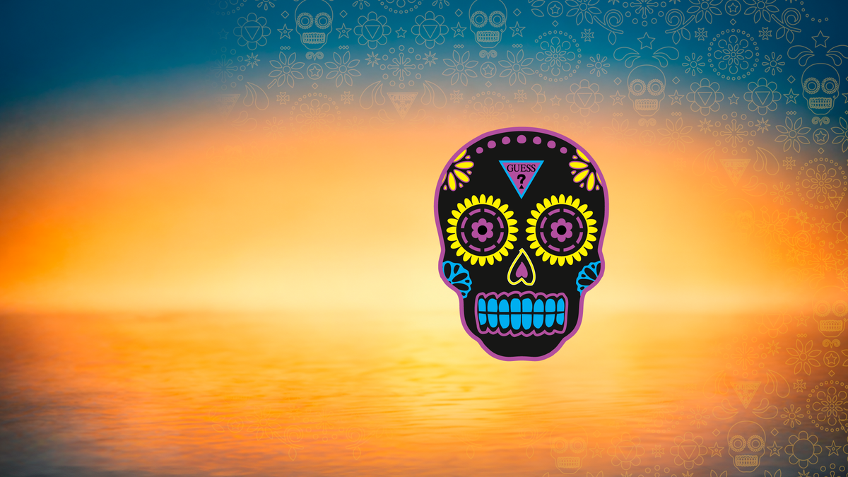 A colorful sugar skull graphic centered over a sunset landscape with orange and yellow tones, plus a blue sky with repeating skull motifs in the background.
