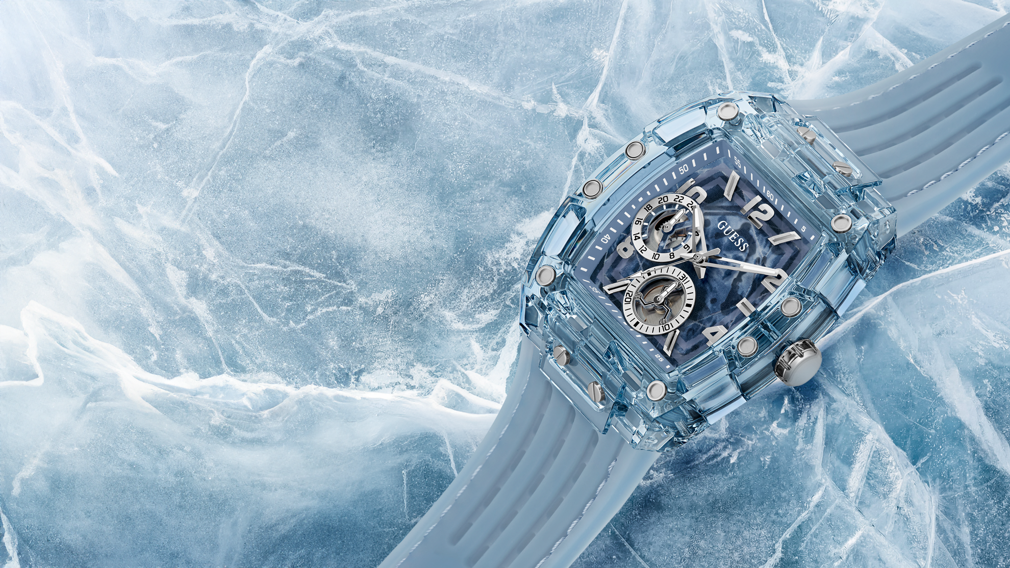 A transparent icy blue watch with a skeleton dial and silver-tone hands, resting diagonally on textured ice with a matching translucent strap.