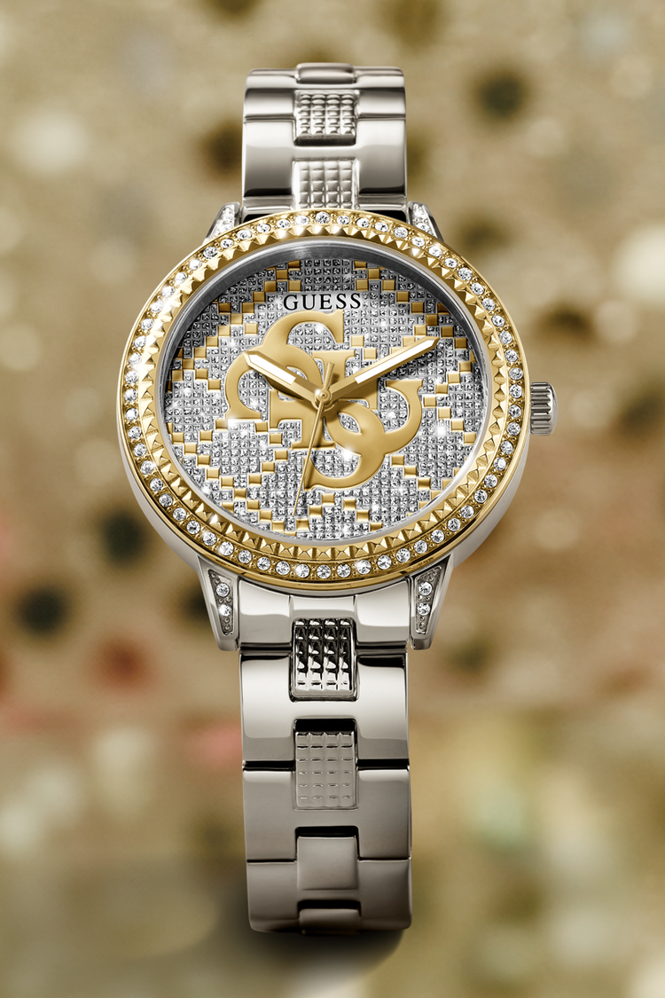 Silver and gold Guess watch with diamond-studded face on a blurred background