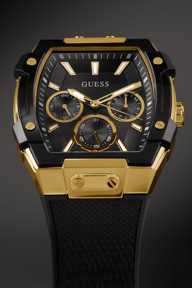 Gold and black Guess watch on a dark background