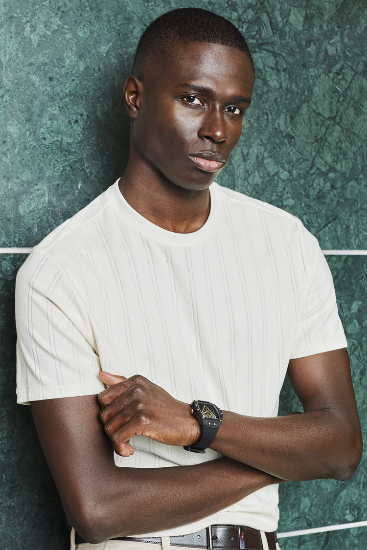 Man wearing a white t-shirt against a textured green wall