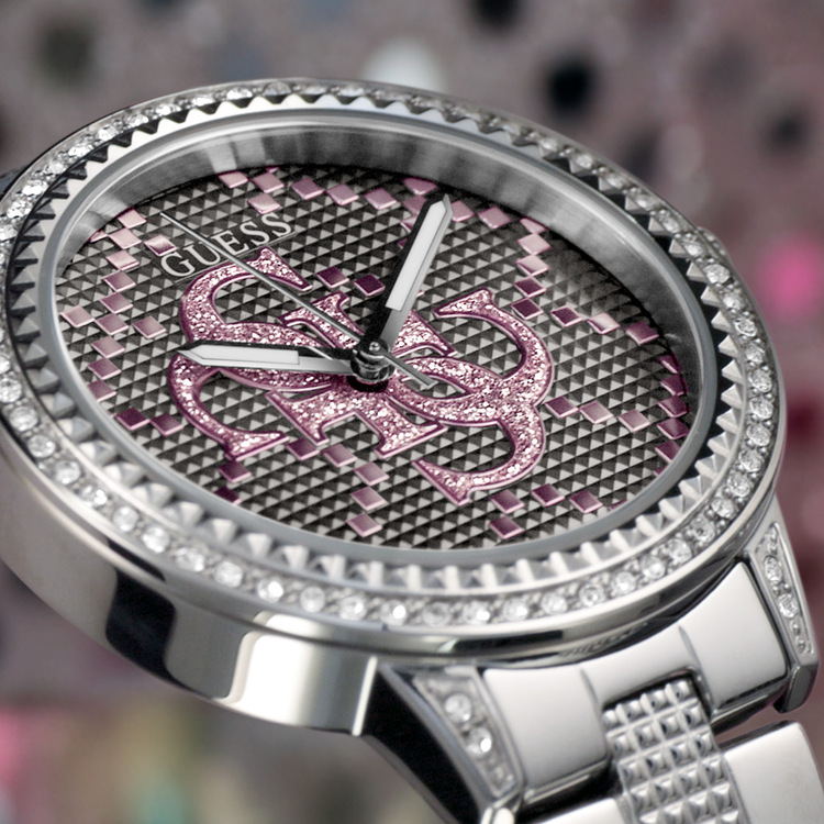 Silver and pink Guess watch with gemstone accents on a blurred background