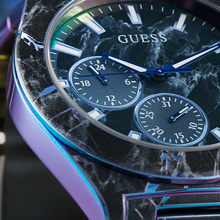 Close-up of a Guess watch with a black marble-like face and blue accents.