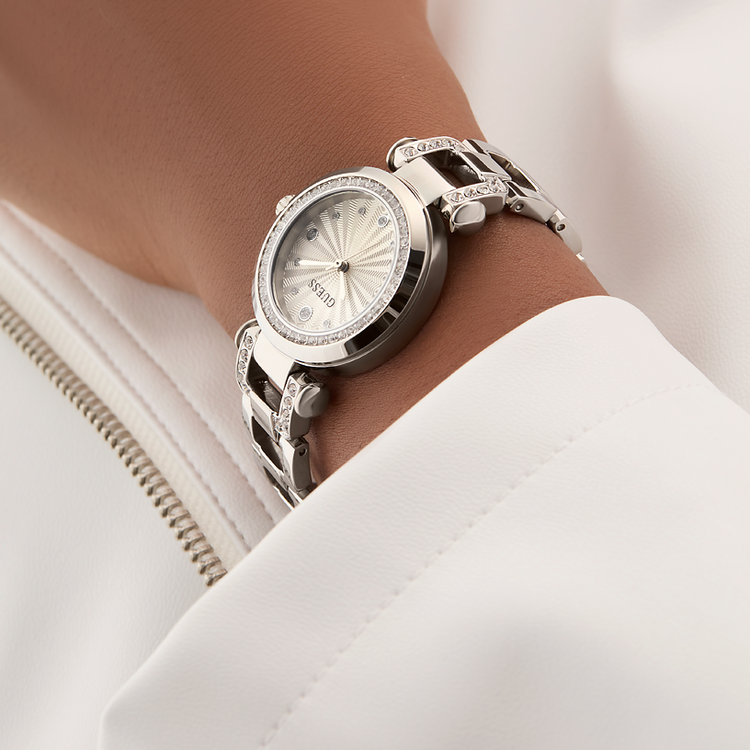 Silver watch with diamond accents on a wrist, close-up against a neutral background