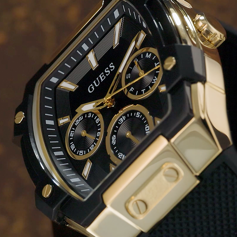 Gold and black Guess watch with detailed design on a dark background