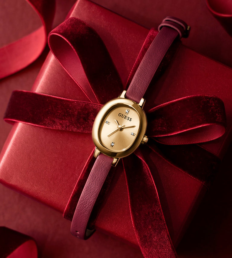 womans gold watch with red strap lying on gift box