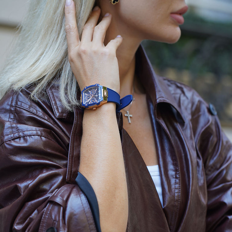 Person wearing a blue wristwatch and bracelet, with a blurred background
