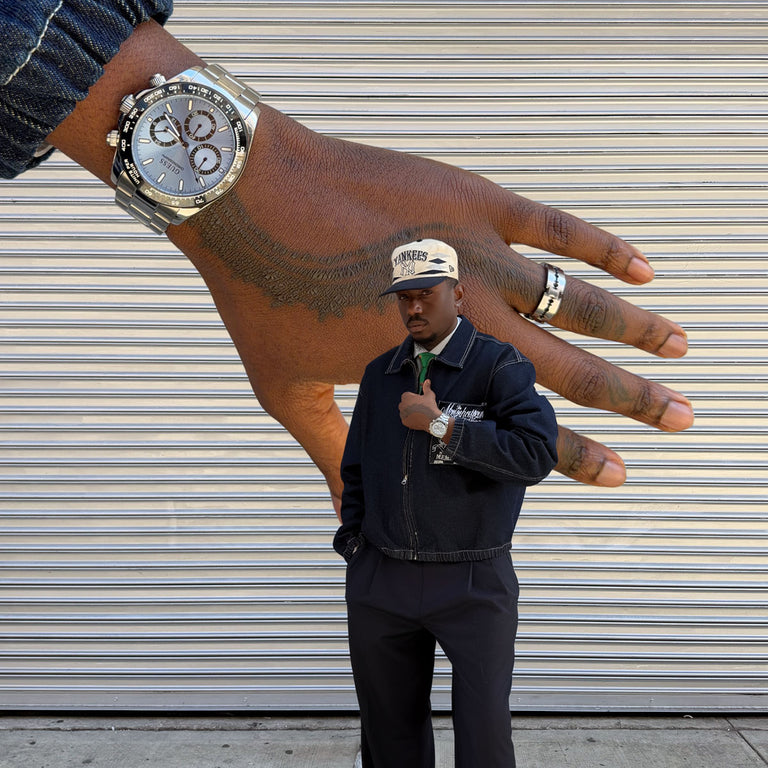 man standing in front of a large hand wearing an Arthur watch