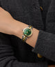 Person wearing a Gc Illusion Small Size Metal gold and silver watch with a green face on a dark background