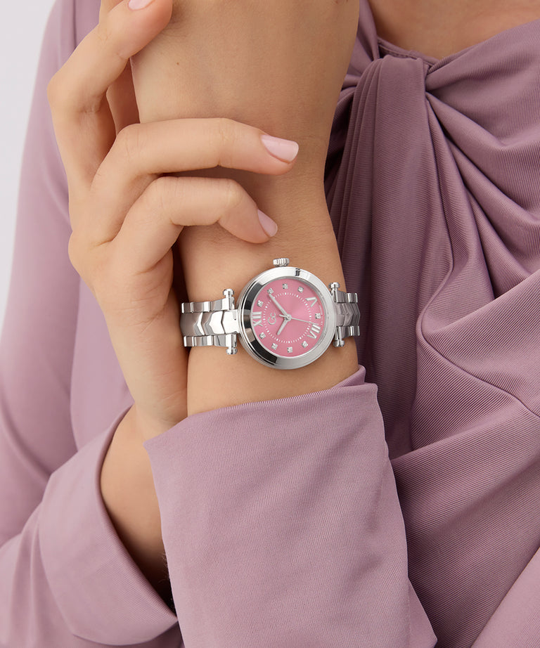 Gc Illusion Small Size Metal watch with pink face on a wrist, wearing a mauve top.