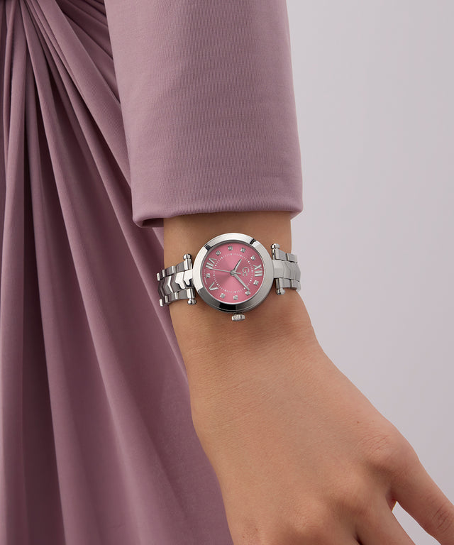 Wrist wearing a silver Gc Illusion Small Size Metal watch with a pink face on a plain background