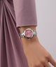 Wrist wearing a silver Gc Illusion Small Size Metal watch with a pink face on a plain background