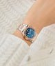 Gc Coussin Shape Mini Small Size Metal Rose gold watch with blue dial on a wrist against a white textured background