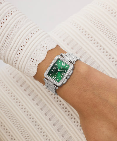 Silver Gc Plaza Mid Size Metal with a green face on a wrist against a white lace background