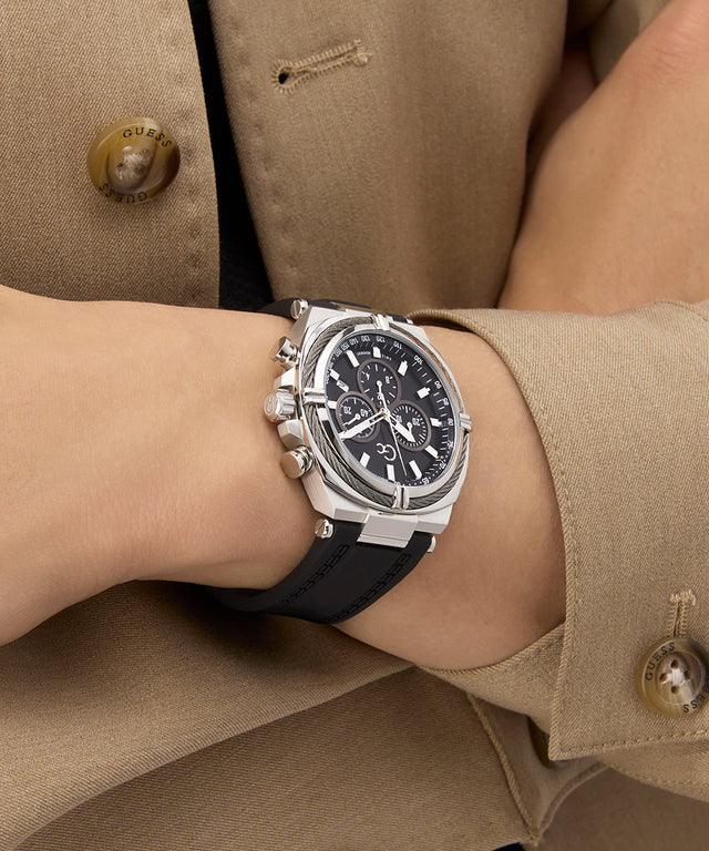 Person wearing a Gc IronClass Chrono Silicone watch with a black strap on a beige jacket background