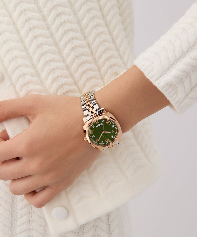 Hand wearing a Gc Flair Coussin Lady Mid Size Metal rose gold watch with a green face on a white textured background