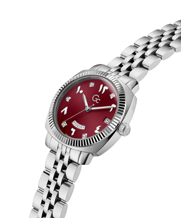 A women's stainless steel watch with a silver-tone link bracelet, featuring a round red dial with silver-tone Arabic numerals and a fluted bezel, shown on a plain white background. lifestyle