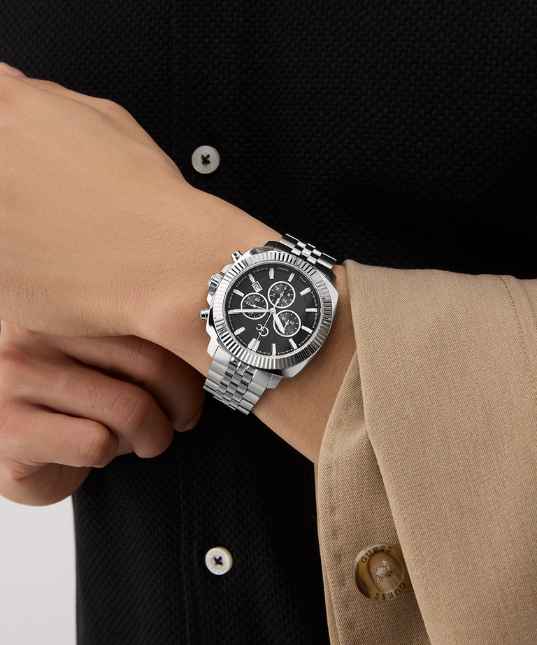 Person wearing a Gc Flair Coussin Chrono Metal silver watch with a black face on a blurred background