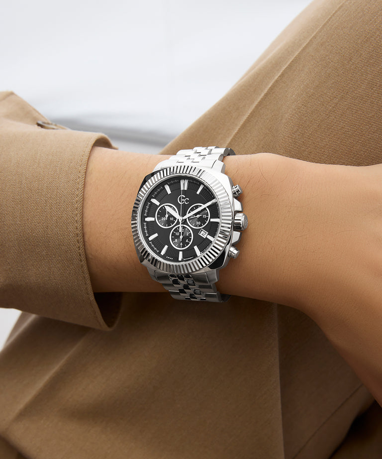 Gc Flair Coussin Chrono Metal Silver watch with black face on a wrist, wearing a brown coat