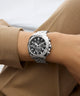 Gc Flair Coussin Chrono Metal Silver watch with black face on a wrist, wearing a brown coat