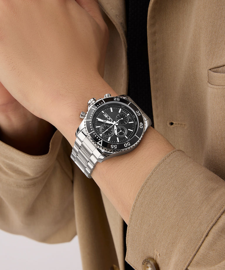 Close-up of a person wearing a silver Gc SpeedRacer Chrono Metal watch with a black face on a beige suit.