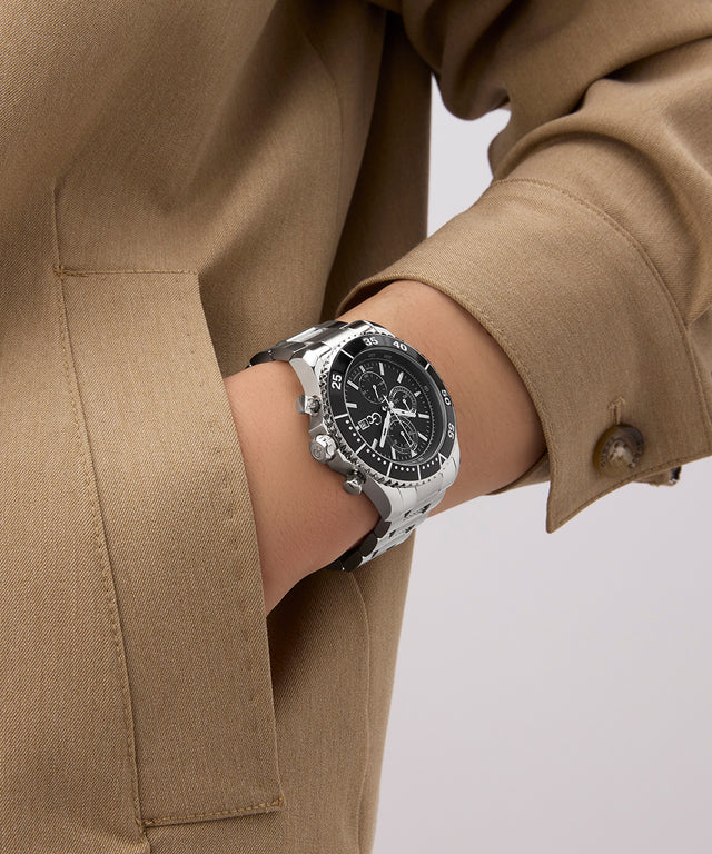 Person wearing a Gc SpeedRacer Chrono Metal silver watch with a beige coat on a light background