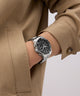 Person wearing a Gc SpeedRacer Chrono Metal silver watch with a beige coat on a light background
