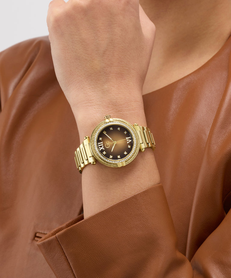 Gold Gc Vogue Cable Mid Size Metal watch on a wrist with a brown leather jacket