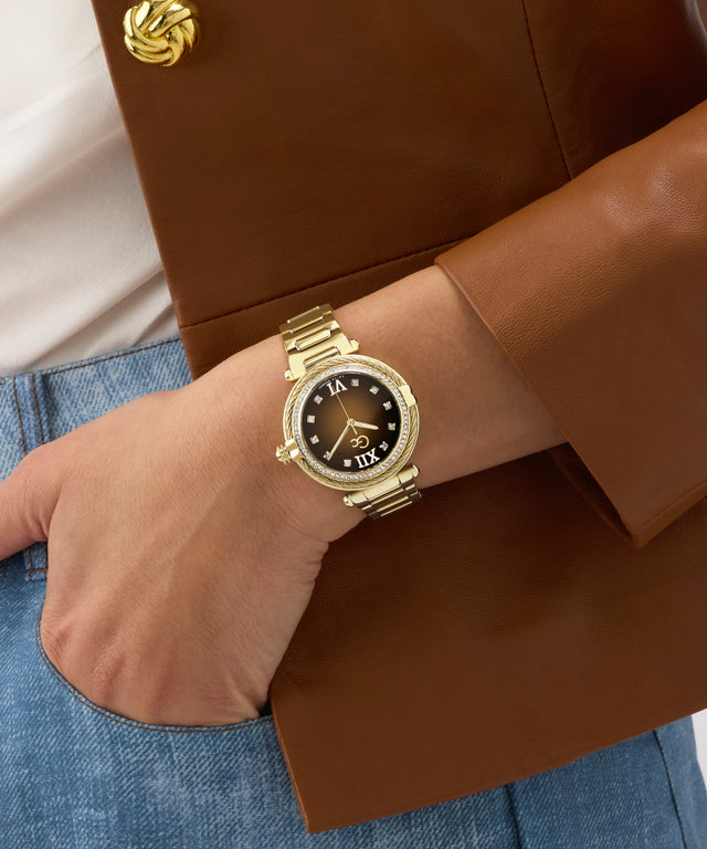 Gold Gc Vogue Cable Mid Size Metal watch on a wrist with a brown coat and blue jeans