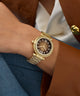 Gold Gc Vogue Cable Mid Size Metal watch on a wrist with a person wearing a brown blazer and white shirt.
