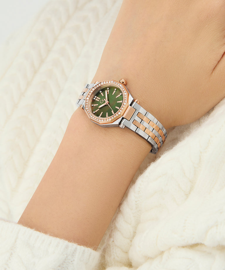 Wrist wearing a Gc Gleam Mini Small Size Metal silver and rose gold watch with a green face on a white background