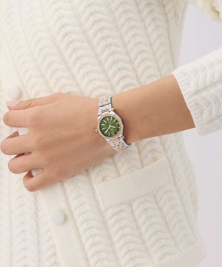Hand wearing a Gc Gleam Mini Small Size Metal silver watch with a green face on a white knitted background