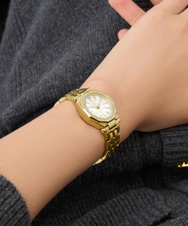 Gc Gleam Mini Small Size Metal Gold wristwatch on a person's wrist with a dark background