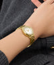 Gc Gleam Mini Small Size Metal Gold wristwatch on a person's wrist with a dark background