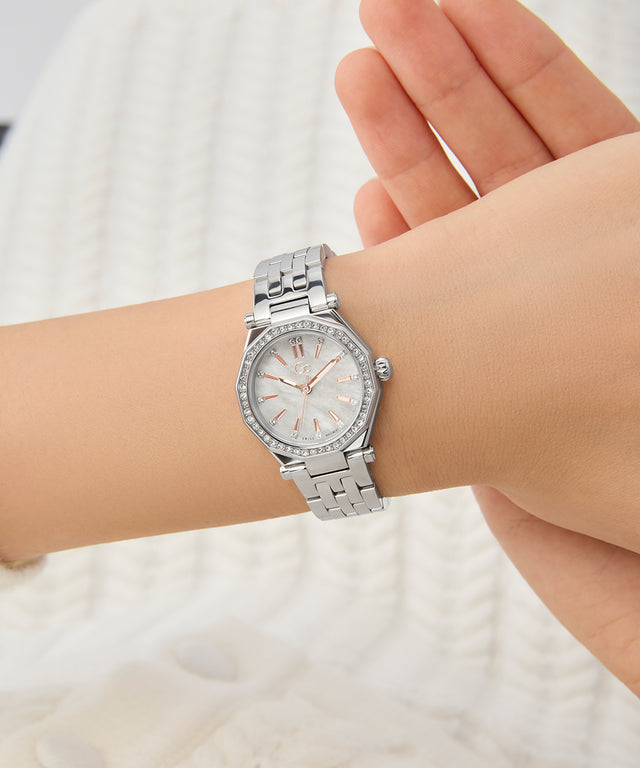 Gc Gleam Mini Small Size Metal Silver wristwatch on a person's wrist with a blurred white background