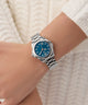 Gc Bolt Lady Mini Small Size Metal Silver watch with a blue face on a wrist against a white textured background