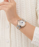 Wrist wearing a Gc TopChic Large Size Metal silver watch with a detailed face against a white textured background