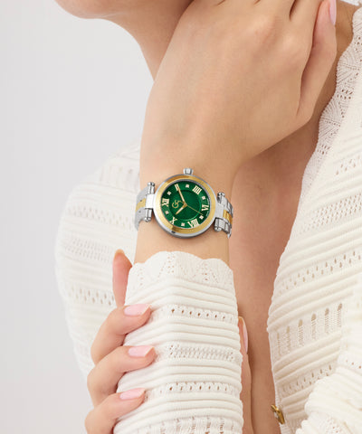 Close-up of a wrist wearing a silver and green Gc TopChic Mid Size Metal watch against a white background