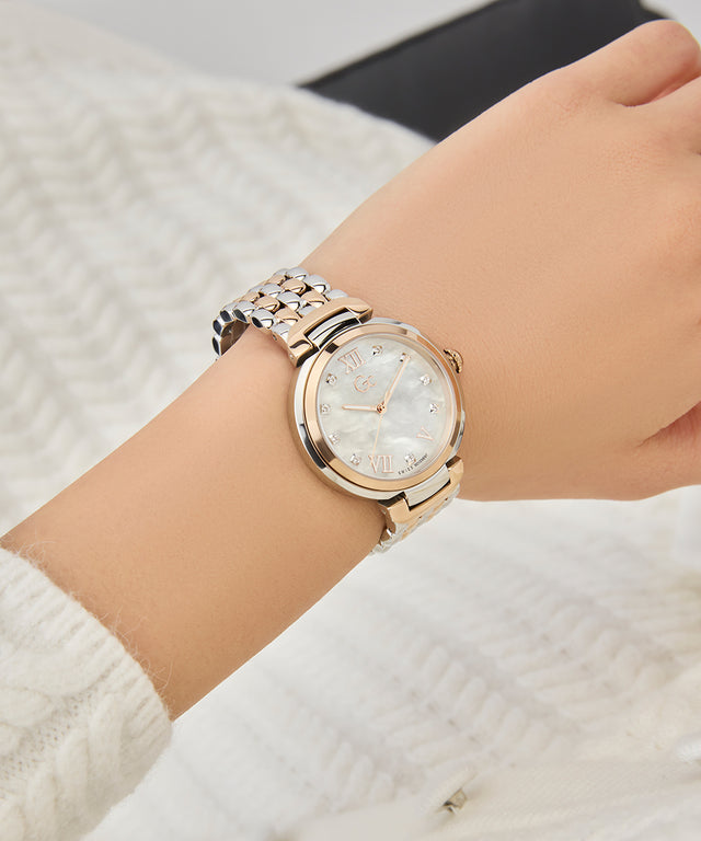 Close-up of a wrist wearing a Gc Allure Mid Size Metal rose gold watch with a textured white background