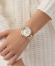 Gc Allure Mid Size Metal Rose gold watch on a wrist against a white textured background